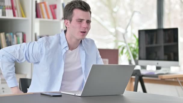 Νεαρός με πόνο στην πλάτη που εργάζεται στο Laptop - Πλάνα, βίντεο