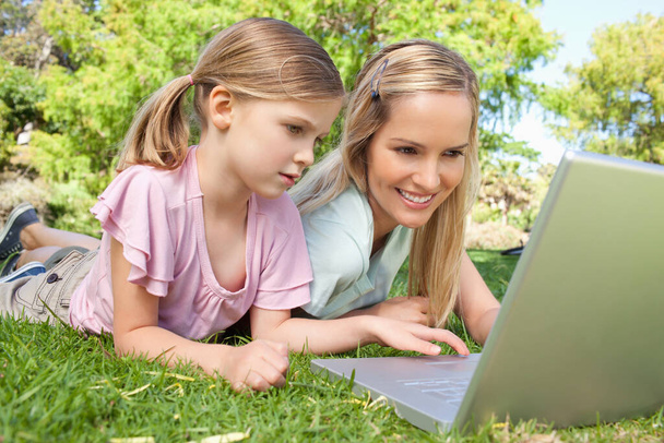 Mother and daughter using the laptop together in the park - Fotó, kép