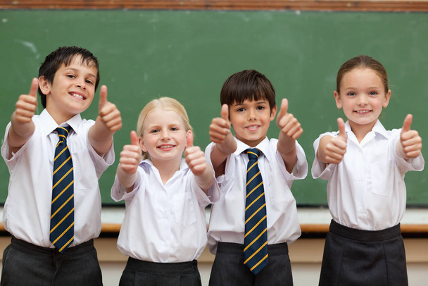 Schoolchildren in school uniforms giving thumbs up - 写真・画像