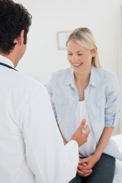 Taustakuva lääkäristä puhumassa hymyilevän potilaansa kanssa
 - Valokuva, kuva