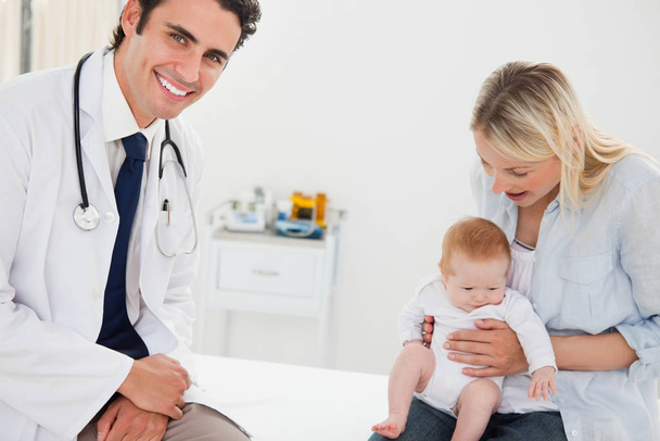 Smiling doctor with a mother and her baby - Foto, Bild