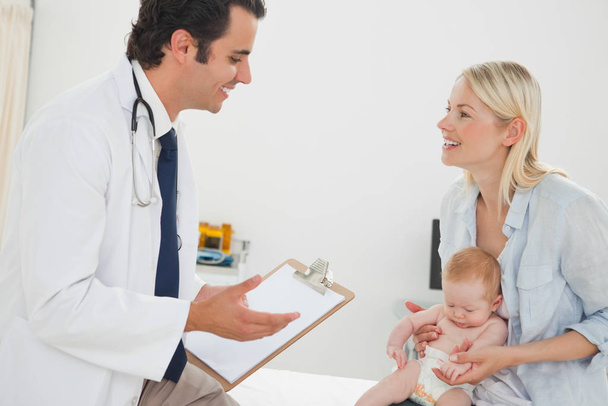 Doctor talking with mother about her baby - Foto, Imagen