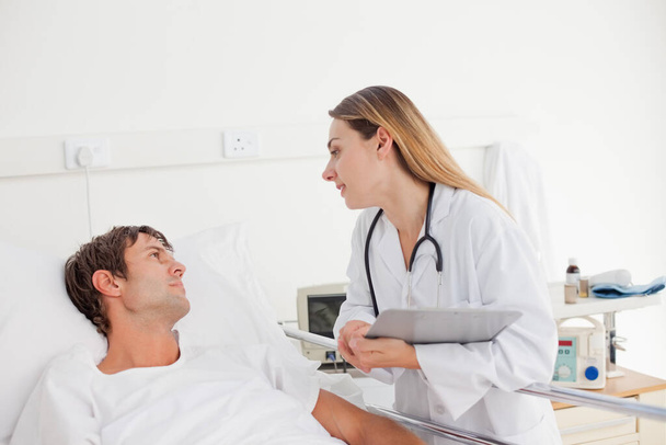 Doctor talking with her patient who is lying in a hospital bed - Foto, imagen