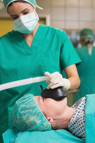 Enfermera cuidando de la máscara de oxígeno del paciente en un quirófano
 - Foto, Imagen