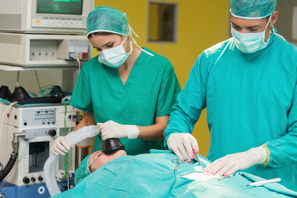 Serious surgeon operating a patient in an operating theatre - Foto, Imagem