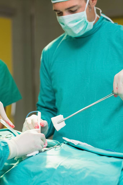 Close up of surgeons holding surgical tools in an operating theatre - Foto, imagen