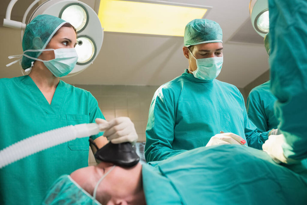 Nurse holding a mask while looking at surgeon in an operating theatre - Foto, Imagem