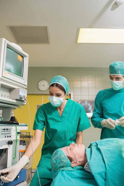 Nurse adjusting the monitor in an operating theatre - Foto, imagen