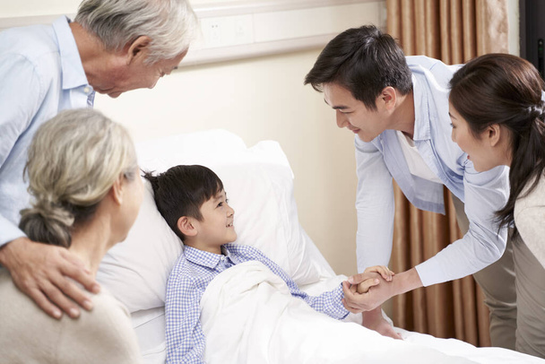 Ασιάτες γονείς και παππούδες που επισκέπτονται νοσηλευμένο παιδί - Φωτογραφία, εικόνα