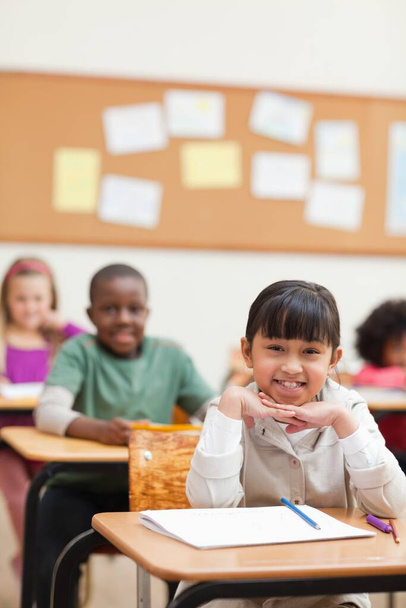 Smiling elementary student sitting at her desk - Foto, Imagem