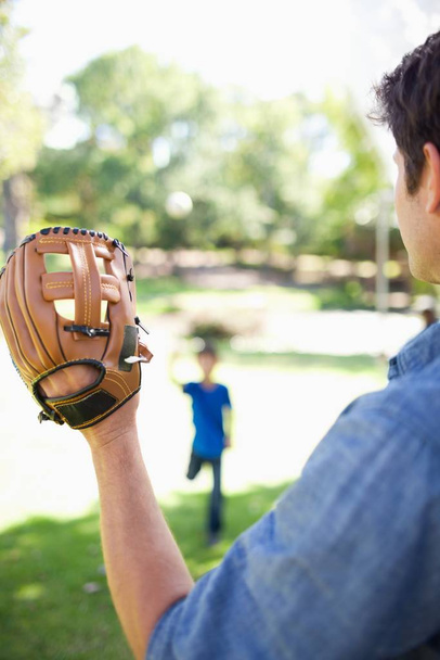 Son in the background prepares to throw the ball which the father is going to catch - 写真・画像
