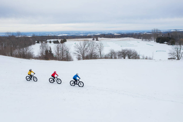 Αεροφωτογραφία drone μιας ομάδας φίλων που κάνουν ποδήλατο στο χιόνι στο Οντάριο του Καναδά - Φωτογραφία, εικόνα