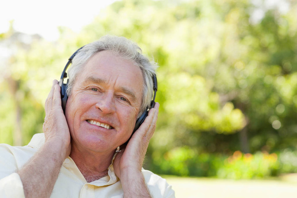 Man smiling as he uses headphones to listen to music - Foto, Bild
