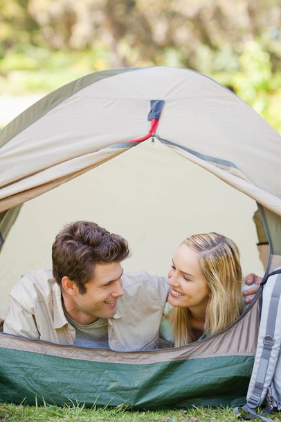 A smiling couple camping as they look at each other - Фото, изображение