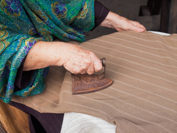 old woman, grandmother irons with historic iron - Zdjęcie, obraz