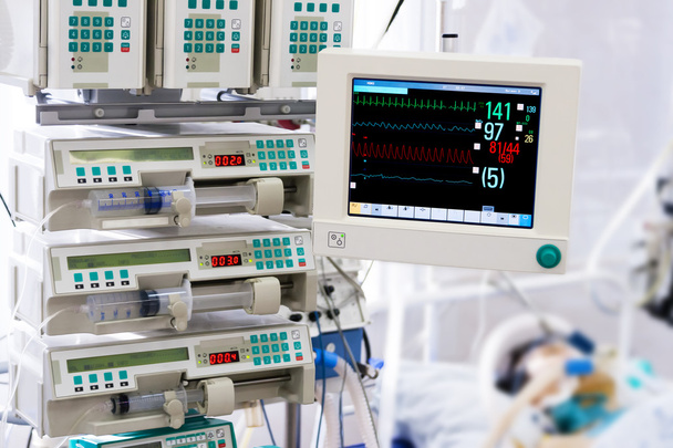 Patient with monitor and infusion pumps in an ICU - Valokuva, kuva