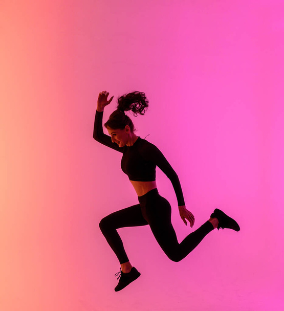 Sports girl on a bright color background does exercises.  - Valokuva, kuva