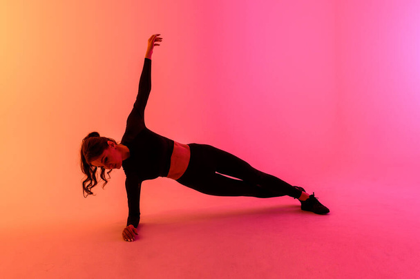 Sports girl on a bright color background does exercises.  - Foto, afbeelding