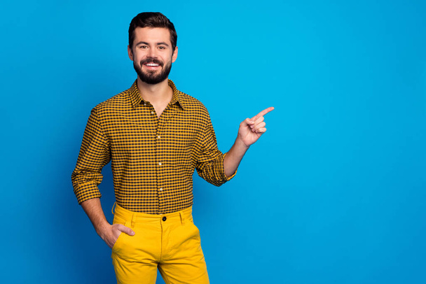 Portrait of positive cheerful man promoter point index finger copyspace indicate adverts promotion suggest select wear stylish checkered clothing isolated over blue color background - Photo, Image