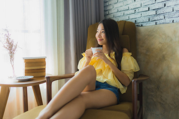 Портрет молодої азіатки сидить на кріслі і читає книгу з
  - Фото, зображення