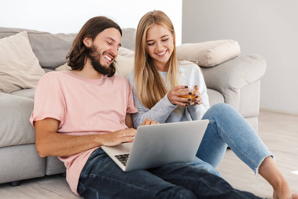 Loving couple near sofa using laptop computer - 写真・画像