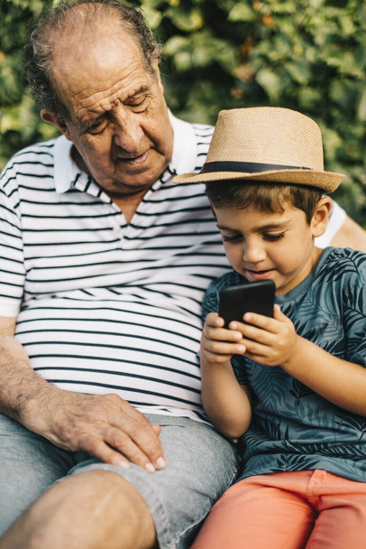 Abuelo y nieto jugando con un teléfono móvil
 - Foto, imagen