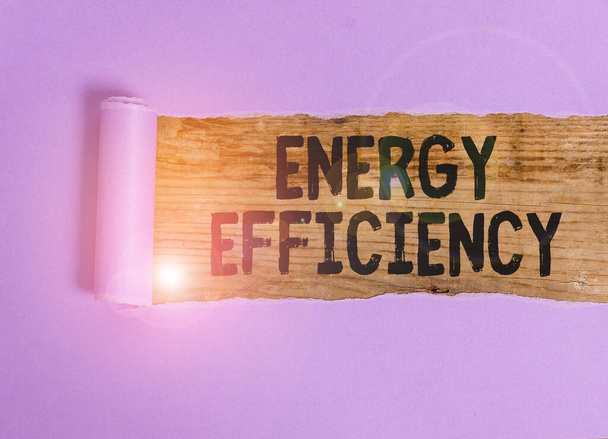 Handwriting text Energy Efficiency. Conceptual photo reduce the amount of energy required to provide product Cardboard which is torn in the middle placed above a wooden classic table - Foto, Imagem