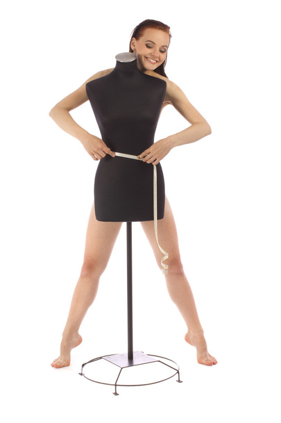 Attractive girl with a measuring tape behind the black mannequin - Photo, Image