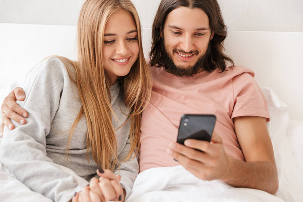 Beautiful young couple sitting in bed at home - Fotoğraf, Görsel