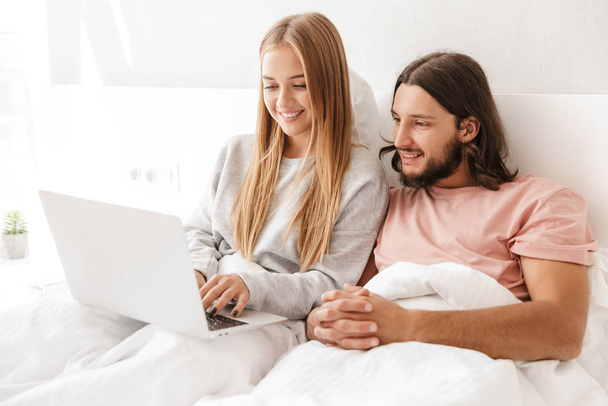 Loving couple in bed using laptop computer indoors at home. - Photo, Image