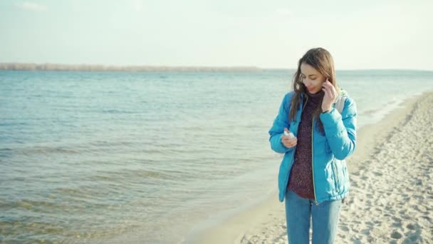 młoda atrakcyjna kobieta za pomocą bezprzewodowych słuchawek na zewnątrz - Materiał filmowy, wideo