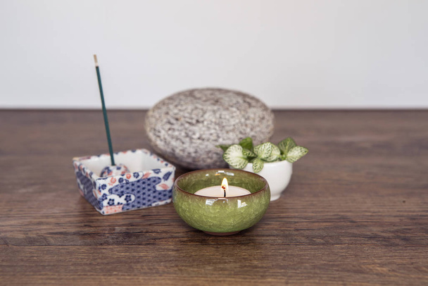 Home altar. Burning candle in a ceramic casing, incense sticks, stone and fresh plants. Spirituality at home concept. Daily meditation routine. Mini Zen Japanese style home altar. Relaxation technics. - Fotoğraf, Görsel