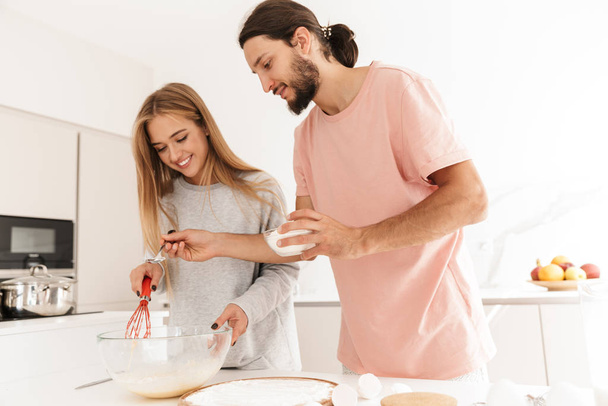Young loving couple at the kitchen indoors at home - Фото, изображение