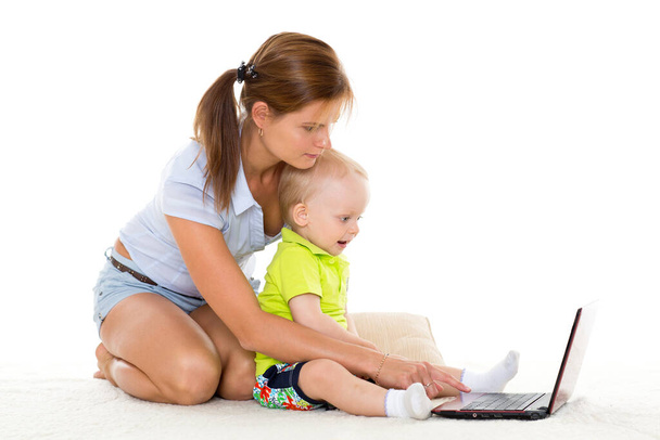 Young mother and her little son with notebook sit on a white background. Happy family. - Foto, Imagen