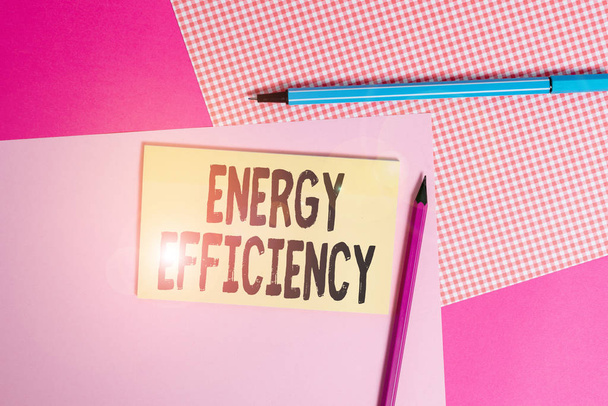 Koncepční rukopis ukazující energetickou účinnost. Koncepce znamená snížit množství energie potřebné k zajištění produktu psaní zařízení a obyčejný poznámkový papír umístěný na stole - Fotografie, Obrázek