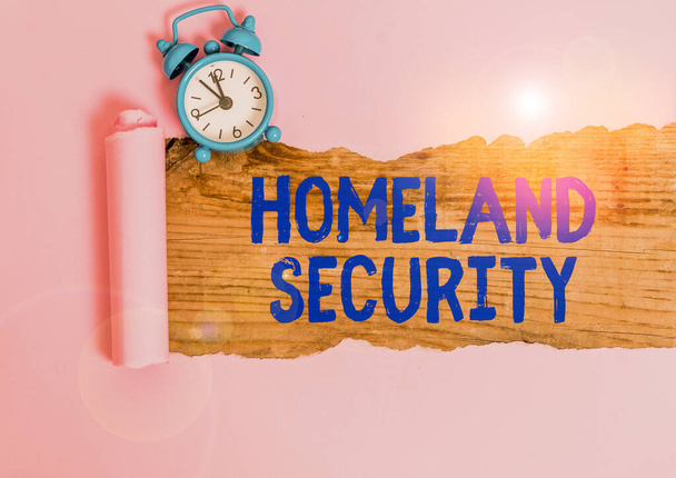 Word writing text Homeland Security. Business photo showcasing federal agency designed to protect the USA against threats Alarm clock and torn cardboard placed above a wooden classic table backdrop - Fotoğraf, Görsel
