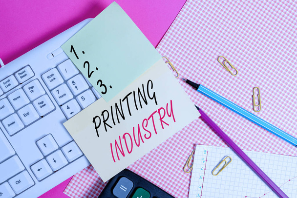 Text sign showing Printing Industry. Business photo showcasing industry involved in production of printed matter Note paper stick to computer keyboard near colored gift wrap sheet on table - Photo, Image