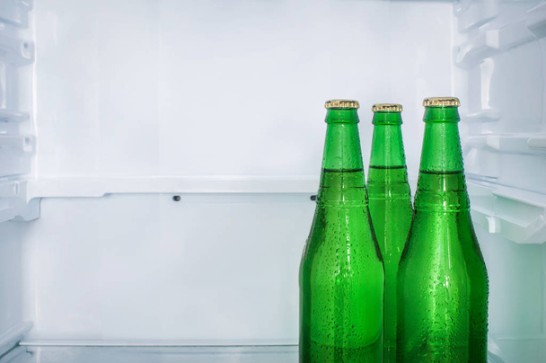 Three sweaty beer bottles on a shelf in an empty refrigerator. Copy space - 写真・画像
