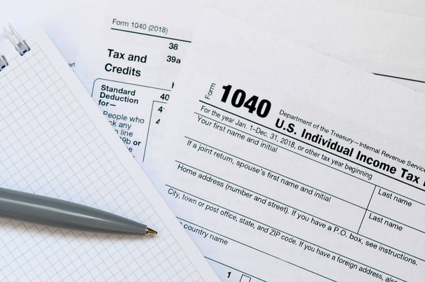 Ручка и ноутбук лежит на налоговой форме 1040 США Индивидуальный
 - Фото, изображение