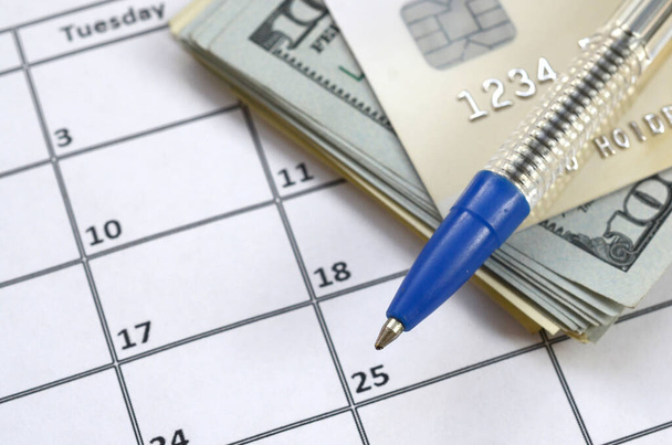 Pen and credit card on many hundred US dollar bills on calendar  - Фото, зображення