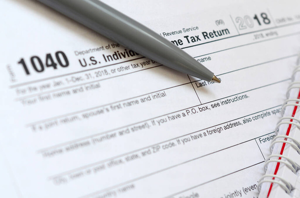 A caneta e caderno está no formulário de imposto 1040 U.S. Individua
 - Foto, Imagem