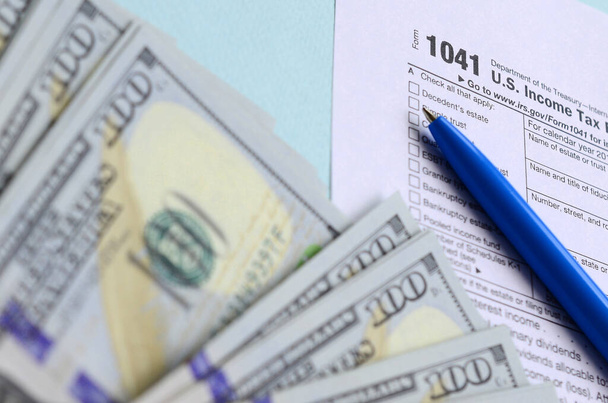 1041 formulario de impuestos se encuentra cerca de cien billetes de dólar y pluma azul en una l
 - Foto, imagen