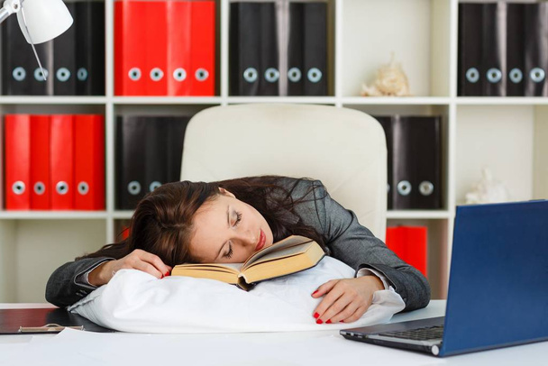 Tired young business woman is sleeping on workplace in the office. - 写真・画像