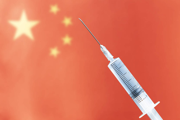 Медичний шприц на тлі блідого прапора Китаю. Копіювальний простір - Фото, зображення