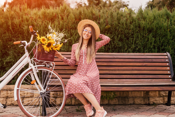 Χαρούμενη γυναίκα με ποδήλατο κάθεται στον πάγκο - Φωτογραφία, εικόνα