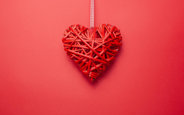 Red wicker heart made of twigs on a red background with place for text - Photo, Image