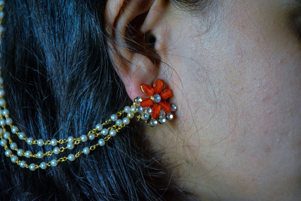 Obrázek bočního pohledu dívčí tváře se zlatou náušnicí s červeným kamenem - Fotografie, Obrázek