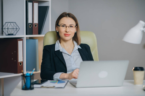 Woman professional using laptop sit at office desk, happy female customer make confirming online website. - Фото, зображення