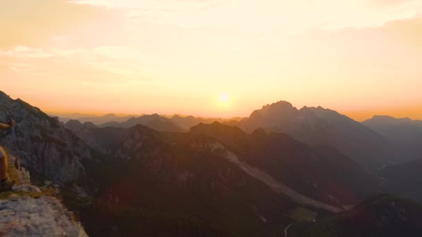 Légi: Izgalmas túrázó kinyújtja karját, miközben nézi a naplementét egy szikláról. - Felvétel, videó
