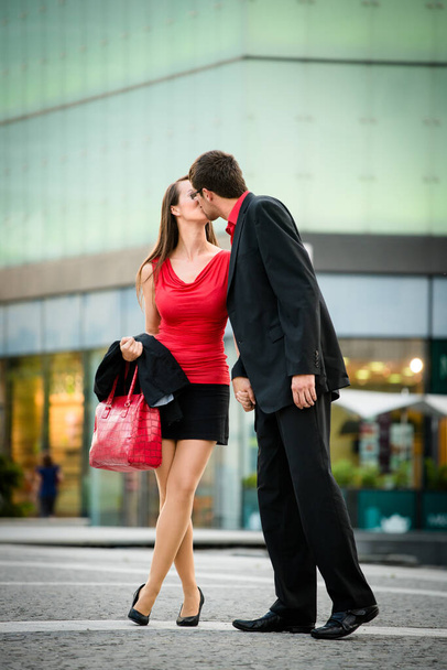 Young business couple dressed in red kiss and welcome each other on street - Fotografie, Obrázek